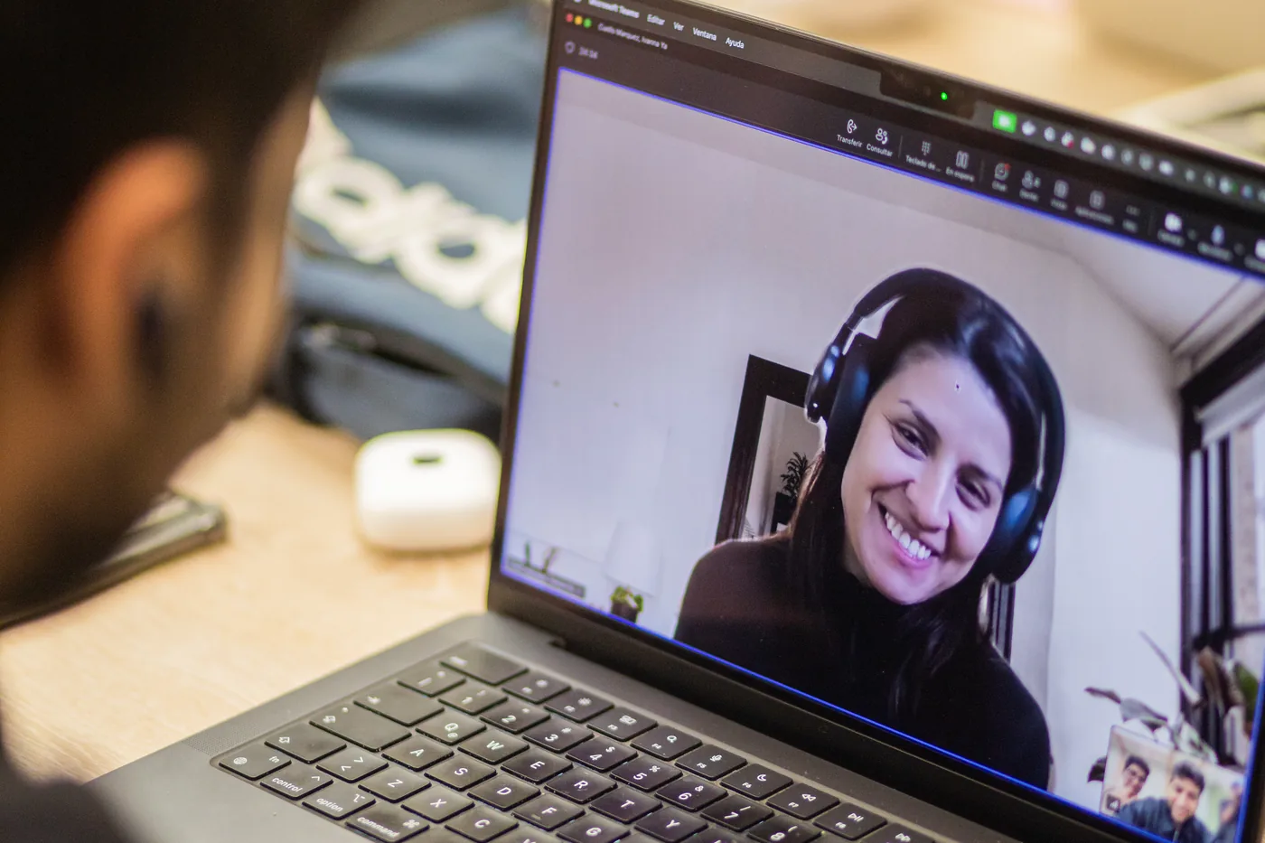 Two engineers pairing over a laptop with a remote teammate on a video call